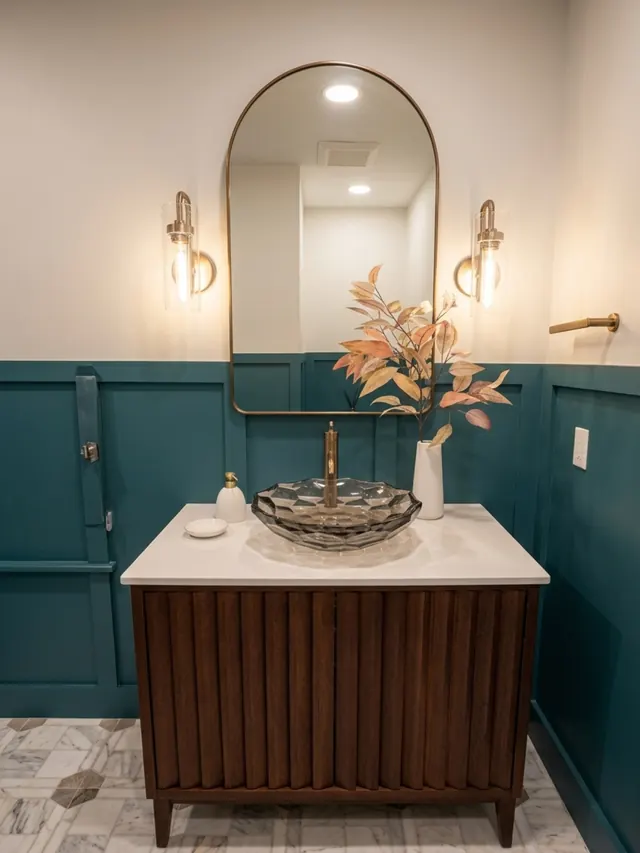 Bathroom with deep green wainscoting, an arched mirror and a wood vanity with a vessel sink