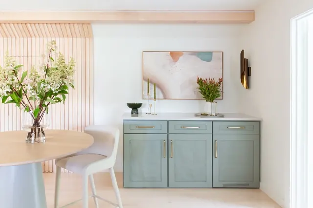Dining nook with a sage green built-in cabinet, round table and slatted wood wall