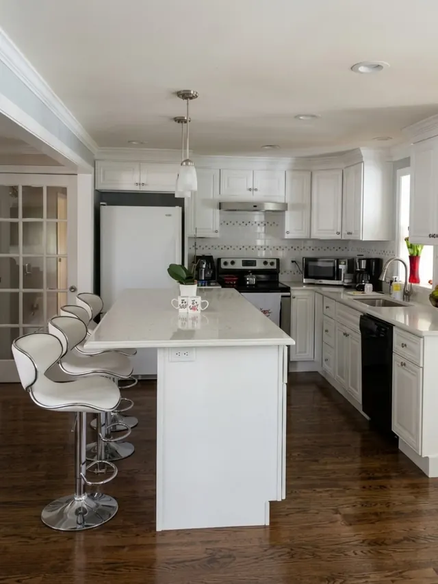 Kitchen remodel with white cabinets, a quartz island with bar stools and hardwood floor