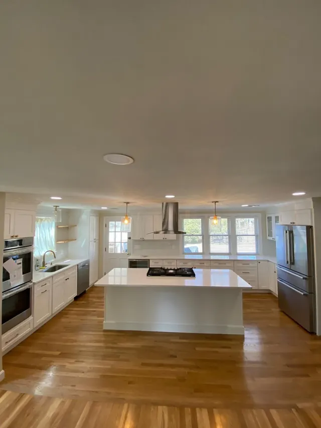 Open kitchen with a white island, gas cooktop and hardwood floor
