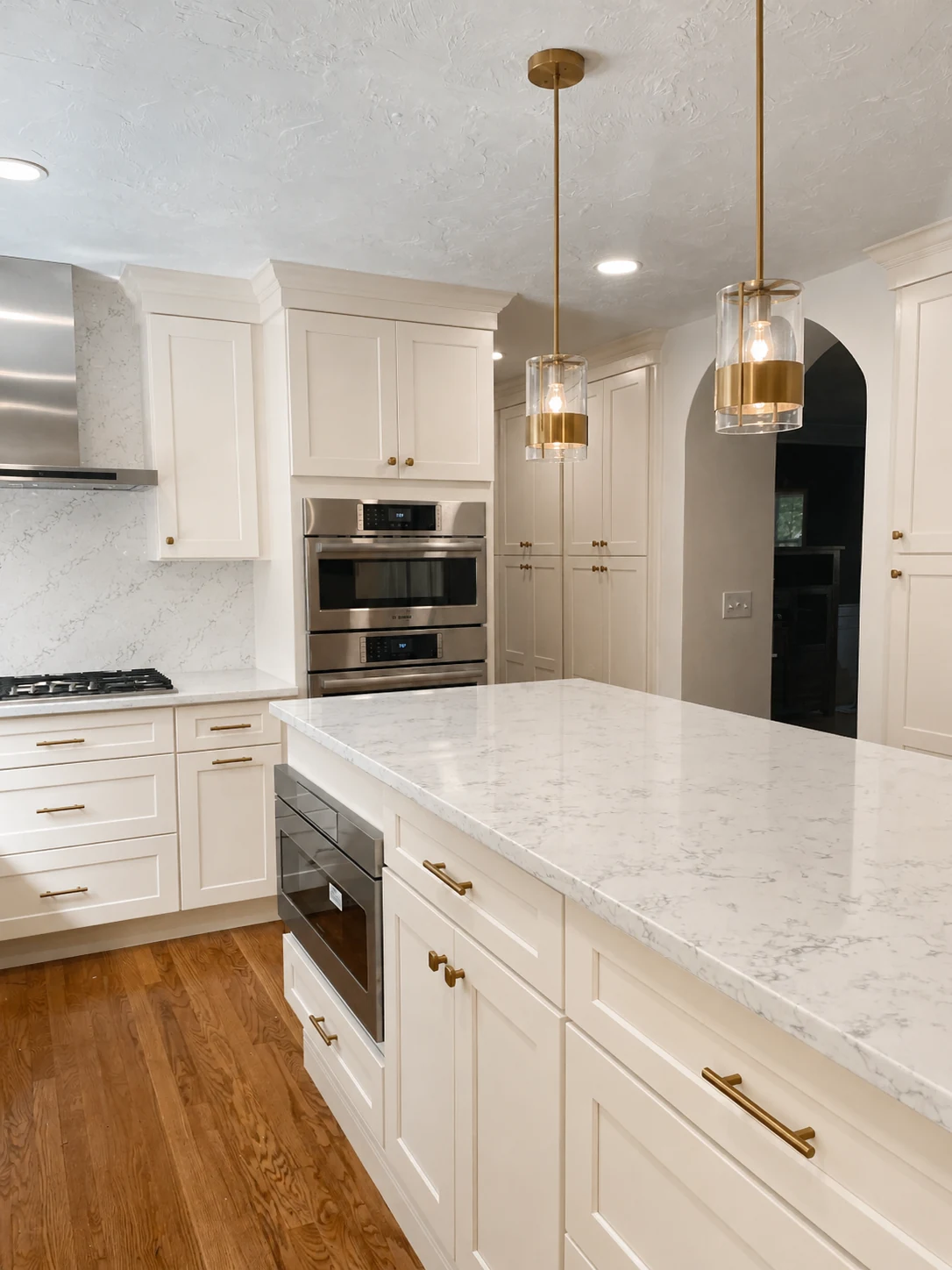Finished kitchen remodel with white cabinets, quartz island and brass hardware in Central Massachusetts