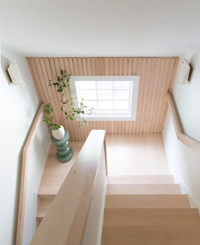Staircase seen from above with a slatted maple wall around the window