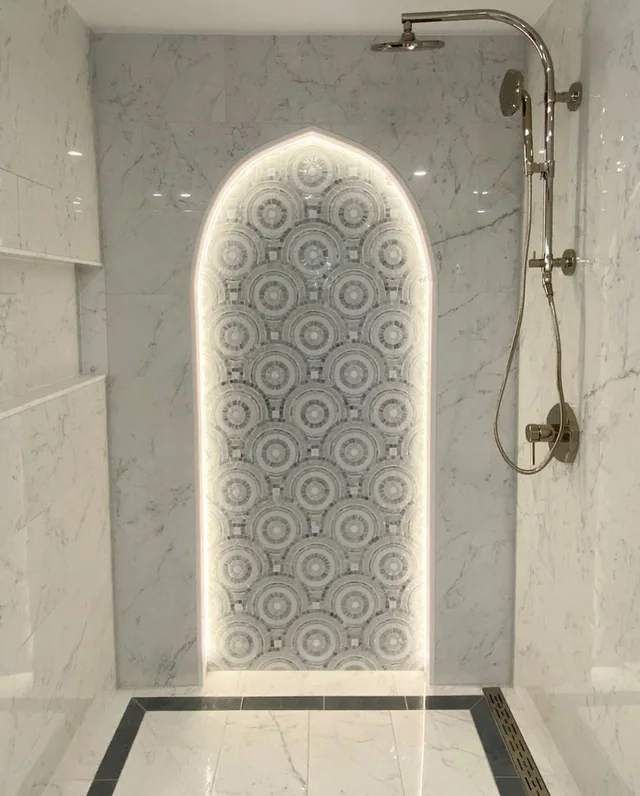 Marble shower with an arched, backlit mosaic niche in a Massachusetts bathroom remodel