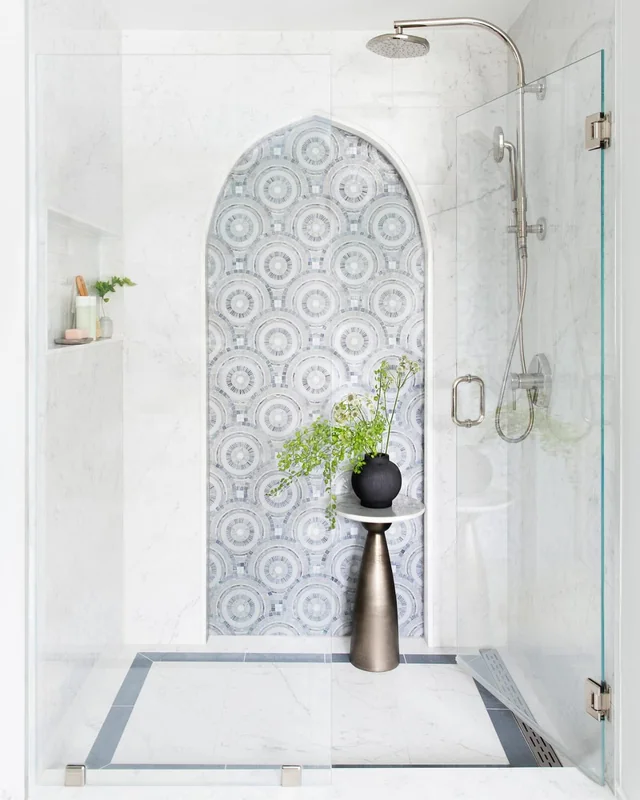 Walk-in shower with an arched mosaic tile niche and frameless glass door in a bathroom remodeled by Mr. Gomes Remodeling