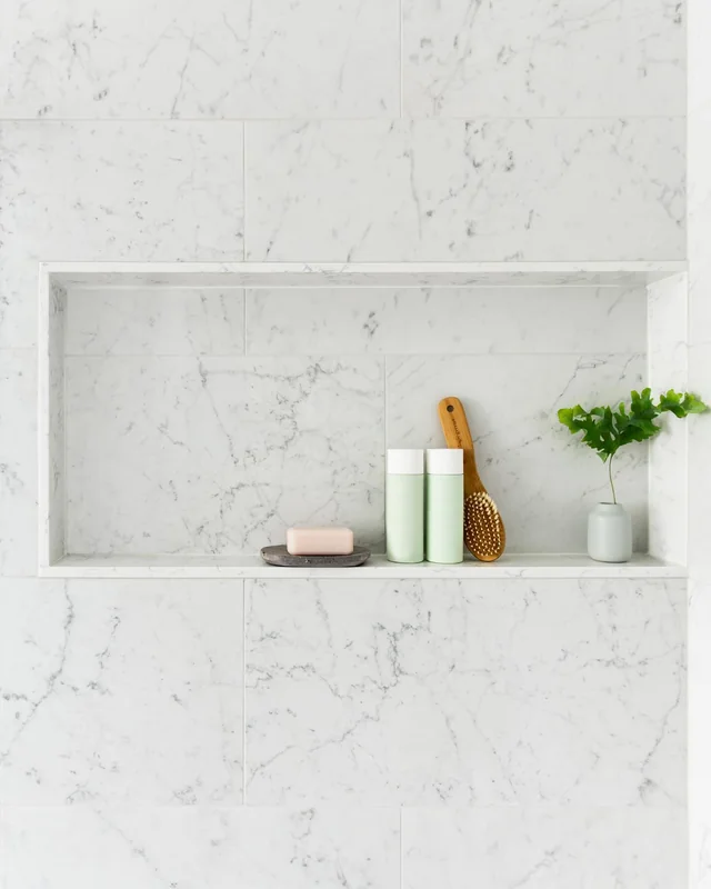 Marble-look shower niche with shelf detail in a remodeled bathroom