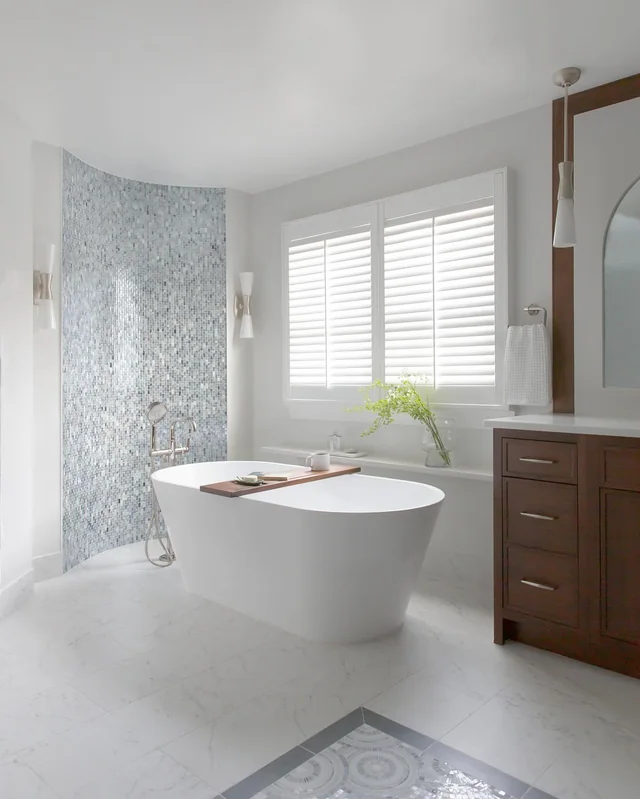 Remodeled bathroom with a freestanding tub, mosaic tile wall and a wood vanity