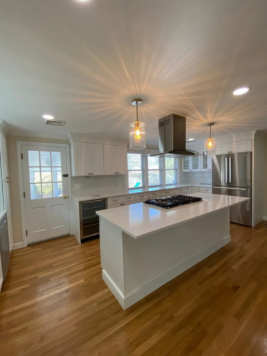Open kitchen remodel with white cabinets, a center island and oak hardwood flooring