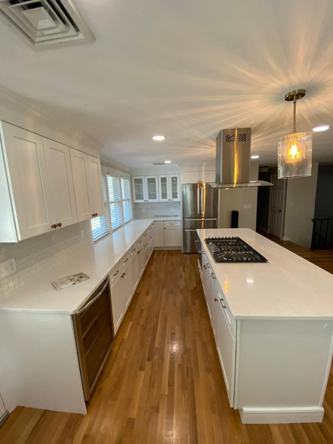 Open kitchen with a white island and hardwood floors in a Massachusetts remodel