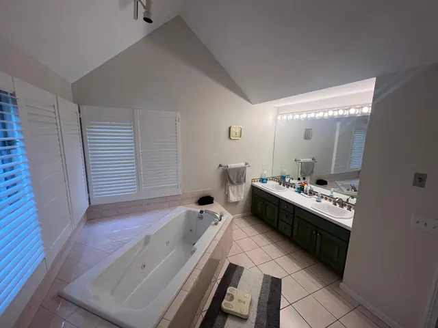 Primary bathroom in Marlborough, MA before the remodel, with a corner jetted tub and shutters