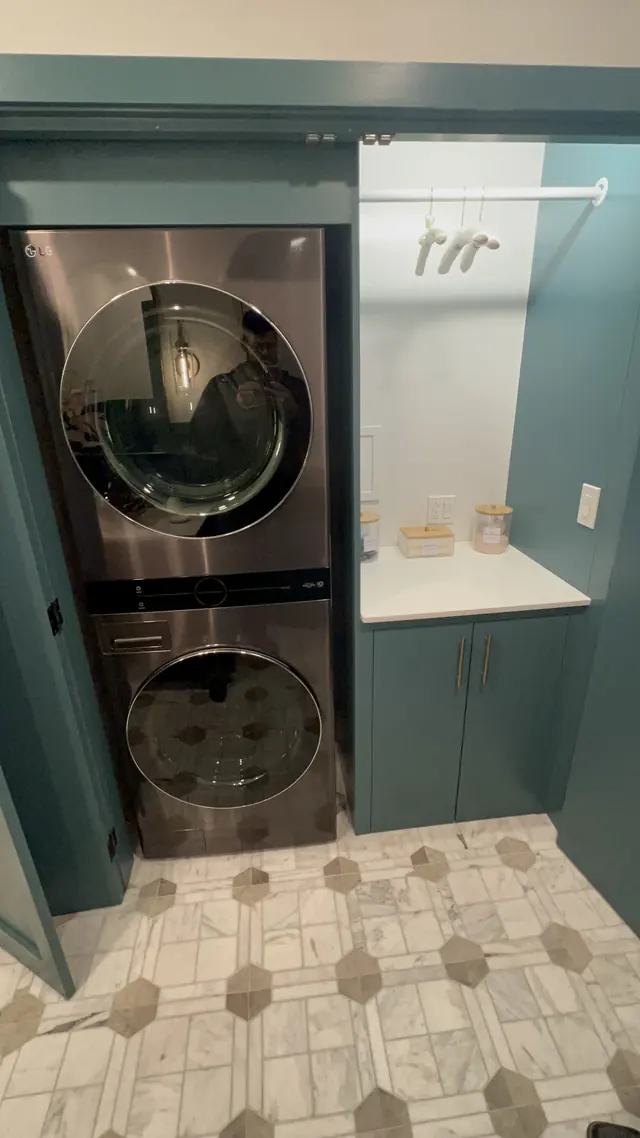 Stacked washer and dryer framed by teal cabinetry after the laundry remodel in Marlborough, MA