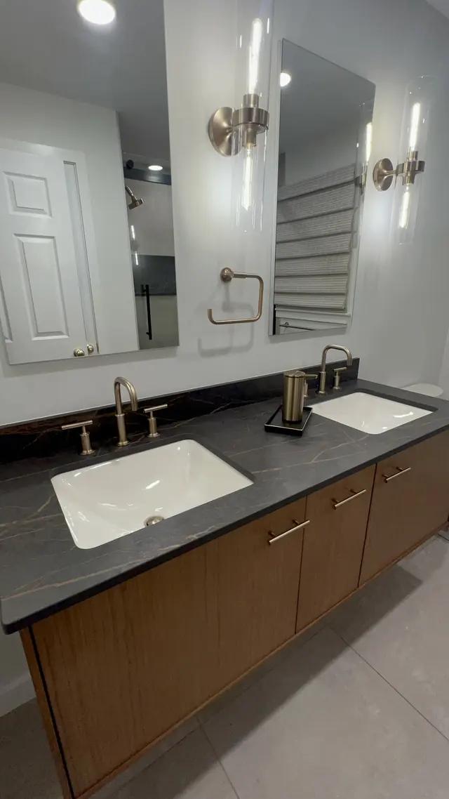 Wood double vanity with two mirrors and brass wall lights after the main bathroom remodel in Marlborough, MA