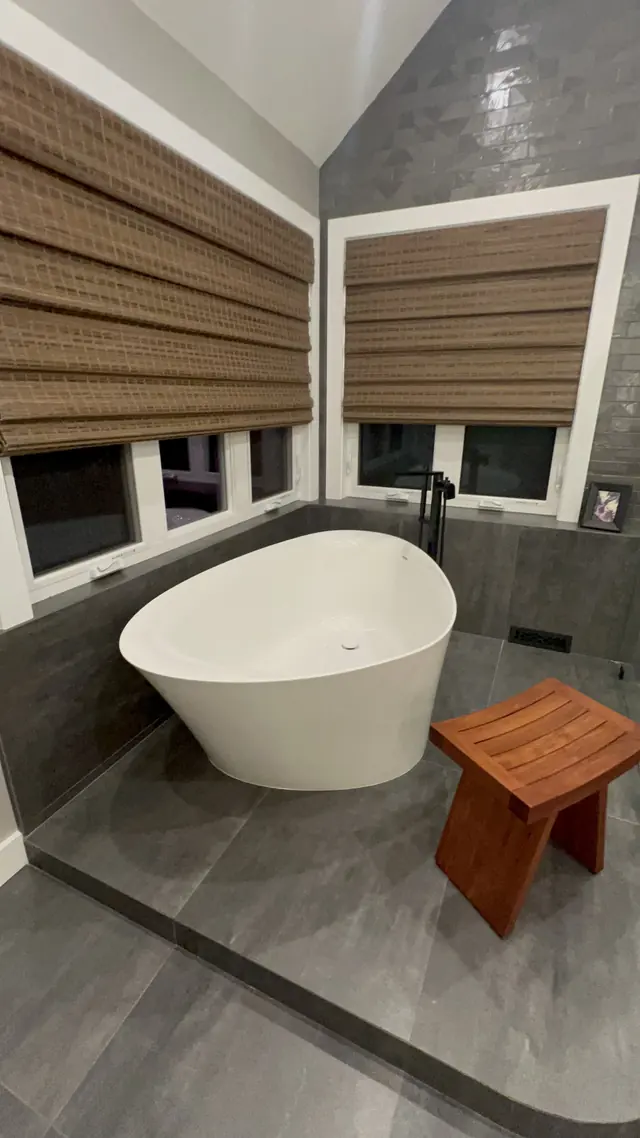Freestanding soaking tub under the windows after the primary bathroom remodel in Marlborough, MA